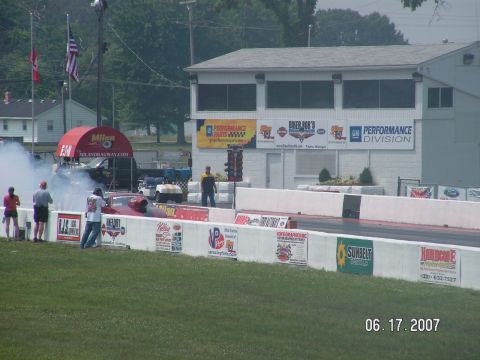 1988 Ford Mustang - A drag car performs a burnout at Milan Dragway, generating smoke as spectators watch.