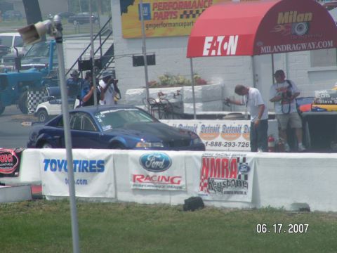 1988 Ford Mustang - A blue coupe sits at a drag strip with various sponsors banners visible.