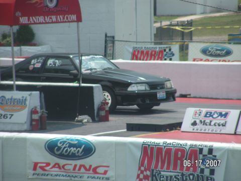 1988 Ford Mustang - A black Ford Mustang is seen at a drag racing event, with various sponsor banners visible.