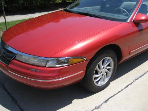 1996 Lincoln Mark VIII - A red 1996 Lincoln Mark VIII convertible is shown from the front quarter angle, highlighting its distinctive grille and headlights.