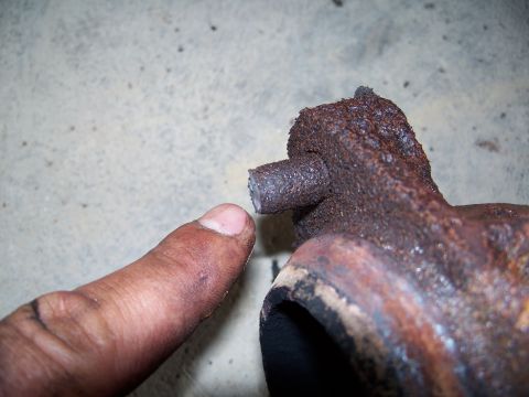 1979 Ford F-150 - A finger points to a broken stud on a heavily rusted exhaust manifold, indicating a part failure.