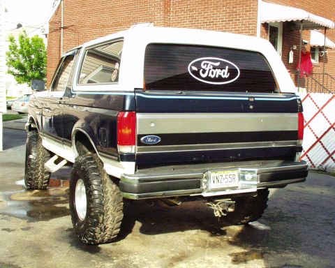 1989 Ford Bronco - This 1989 Ford Bronco is shown from the rear, a dark blue and white color scheme and lifted suspension with large off-road tires.