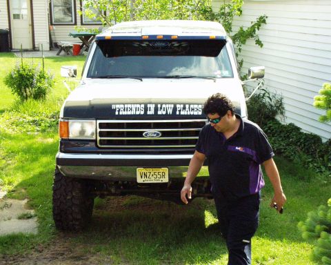 1989 Ford Bronco - A man walks past a lifted Ford Bronco with a custom decal on the hood.