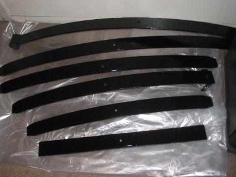 1991 Ford Bronco - Several black leaf springs are arranged on a clear plastic sheet on the floor.
