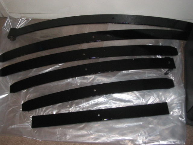 Black leaf springs laid out on plastic sheeting