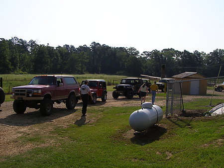 1995 Ford Bronco - Several SUVs are parked in a grassy lot near a building and a propane tank.