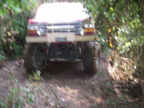 1995 Ford Bronco - 1995 Ford Bronco navigating a muddy, wooded trail.