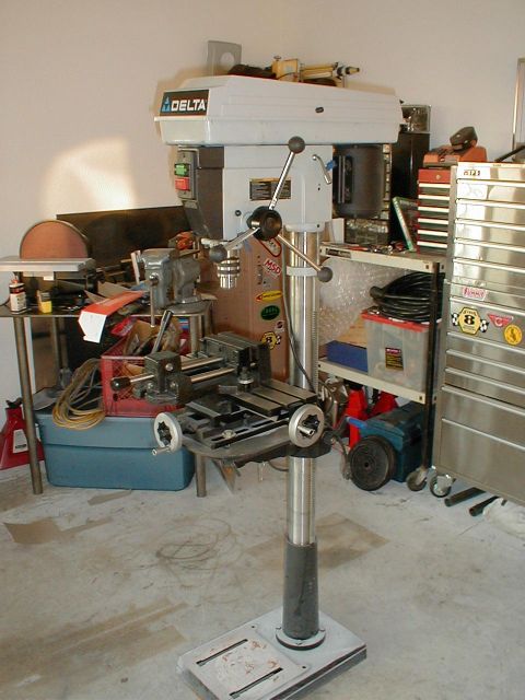 1996 Ford Bronco - A Delta drill press is equipped with a milling vise, surrounded by various tools and storage units in a workshop setting.