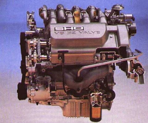 1997 Ford Taurus - Studio cutaway photo of an SHO V8 engine on a blue backdrop, with the intake plenum cast "SHO V8 32 VALVE" and the front cover, timing chai…