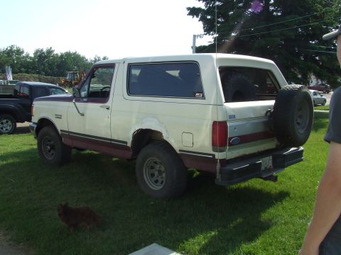 1990 Ford Bronco - This two-tone Ford Bronco is parked on a grassy area with a spare tire mounted on the rear.