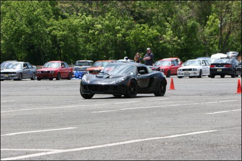 2001 Mercury Grand Marquis - A black sports car navigates a course marked by orange cones, with other vehicles visible in the background.