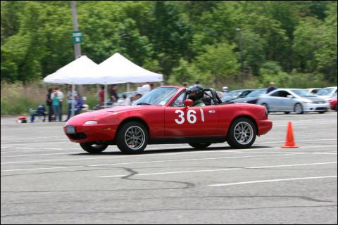 2001 Mercury Grand Marquis - A red convertible sports car with racing number 36 navigates a course marked by an orange cone, with other vehicles and tents in the backgr…
