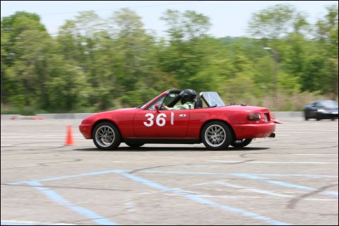 2001 Mercury Grand Marquis - A red convertible with racing numbers participates in an autocross event on a sunny day.