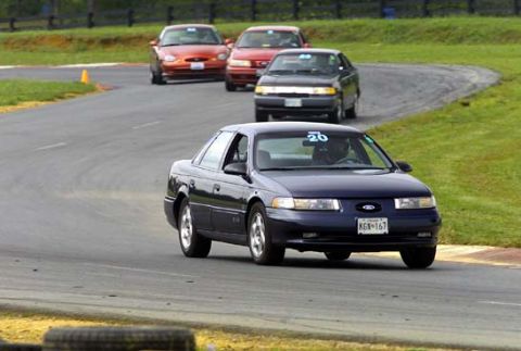 1997 Ford Taurus - A dark blue second-generation Ford Taurus SHO sedan wearing number 20 leads a line of Tauruses through a track corner, followed by a silver…
