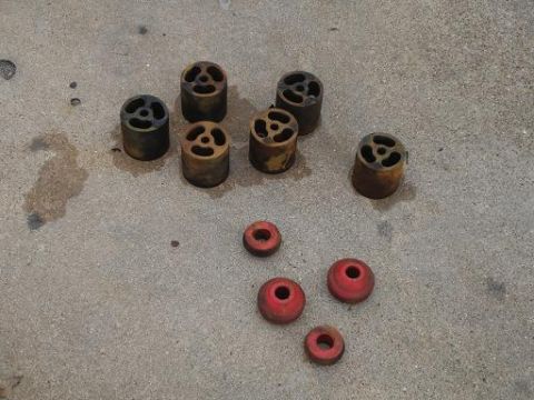 1996 Ford F-150 - Various suspension components, including metal lift blocks and red bushings, lie on a concrete floor.
