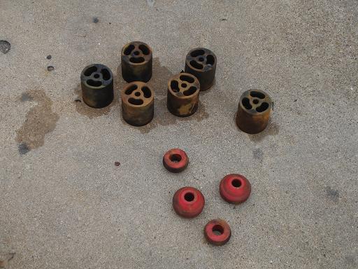 Several metal lift blocks and red rubber bushings scattered on a concrete surface