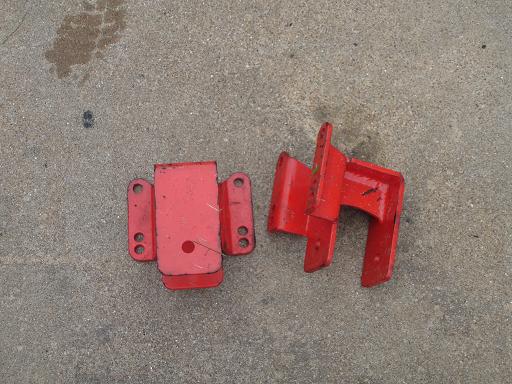 Two red metal brackets on a concrete surface