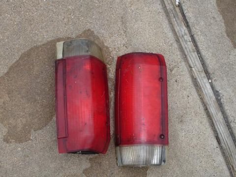 1996 Ford F-150 - Two red plastic tail lights are shown on a concrete surface next to a wooden plank.
