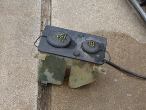 1996 Ford F-150 - A detached windshield washer fluid reservoir sits on a concrete surface.
