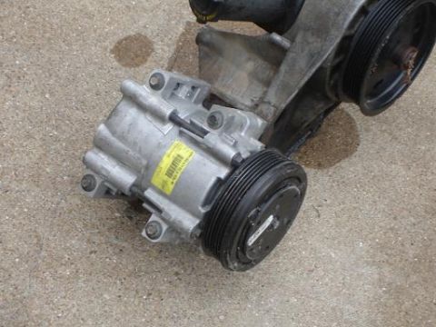 1996 Ford F-150 - A close-up view of an air conditioning compressor, likely a replacement part, resting on a concrete surface.