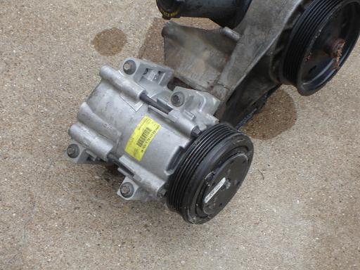 Air conditioning compressor with yellow sticker and pulleys