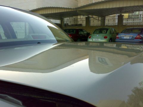 2007 Mercury Grand Marquis - Reflection of a building and parked cars on the hood of a silver vehicle.