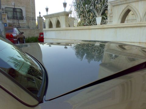 2007 Mercury Grand Marquis - Reflection on car hood shows ornate fence and building details.