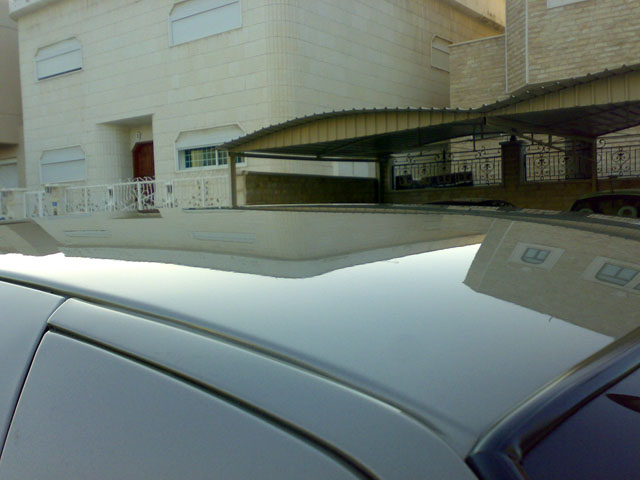 Reflection of a building on a car's roof, with a Supermotors.net watermark