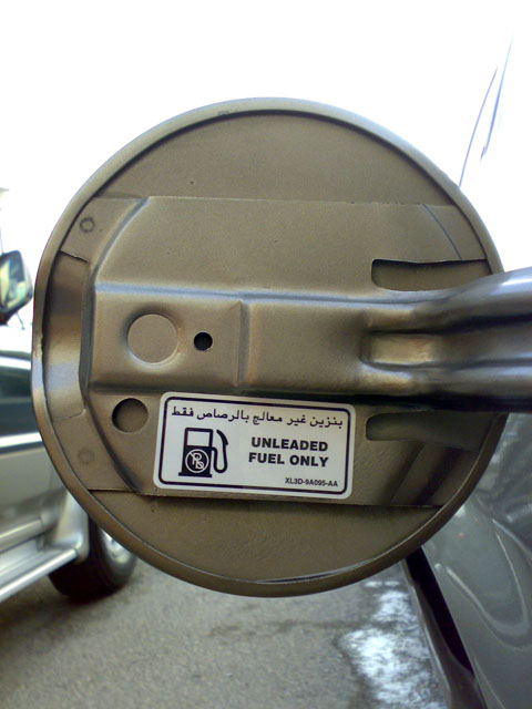 2007 Mercury Grand Marquis - A close-up of a vehicle's fuel filler door shows an "UNLEADED FUEL ONLY" sticker with Arabic text.