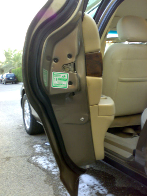 2007 Mercury Grand Marquis - The interior door jamb of a vehicle, showing a green sticker with text and beige upholstery.