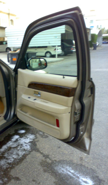 2007 Mercury Grand Marquis - Interior view of a tan door panel with wood trim, reflecting a beige exterior.