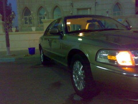 2007 Mercury Grand Marquis - A gold sedan is parked in front of a building with arched windows.