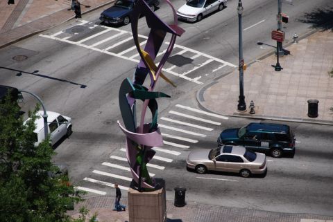 1996 Ford Bronco - An abstract sculpture stands prominently at a city intersection, with several vehicles navigating the street and crosswalks.