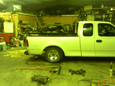 1982 Ford Bronco - A white pickup truck is parked inside a cluttered garage.
