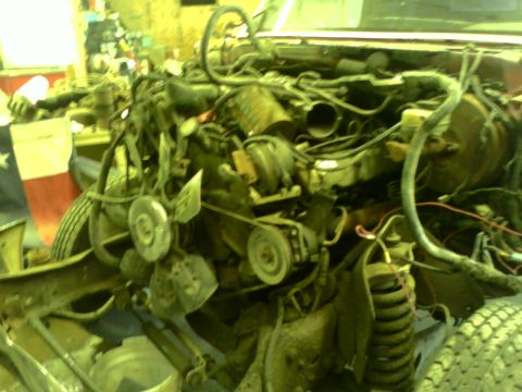 1982 Ford Bronco - The engine bay of a vehicle is shown disassembled, with a Texas flag visible behind it.