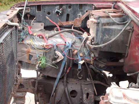 1982 Ford Bronco - The engine bay of a vehicle shows a complex network of exposed wiring and mechanical parts, suggesting a state of disrepair or modification.
