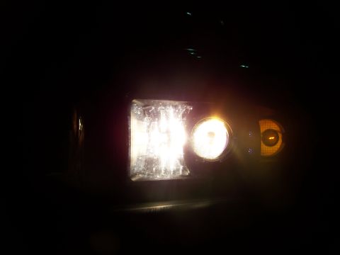 2001 Dodge 1500 - Close-up of a vehicle's headlight assembly, showing the main beam and amber turn signal illuminated in the dark.