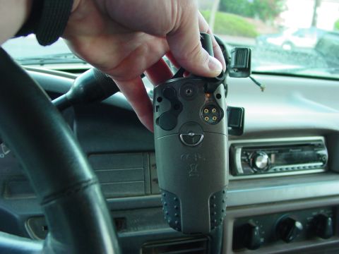1994 Ford Bronco - A hand holds a gray device inside a 1994 Ford Bronco, with the steering wheel and dashboard visible.