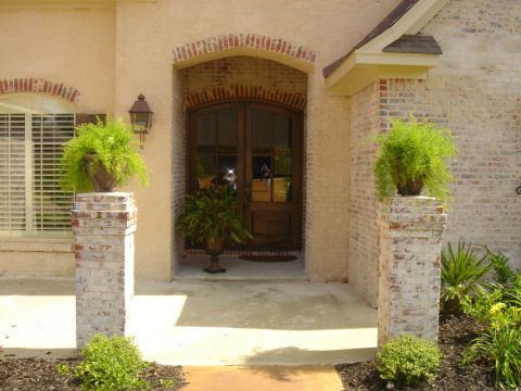 1995 Ford Bronco - The entryway to a home features a covered porch with decorative brickwork and lush greenery.