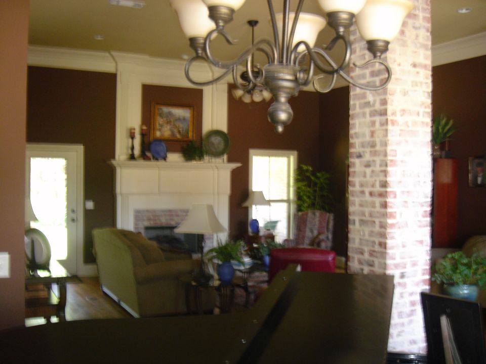 Interior of a living room with a fireplace, chandelier, and brick column