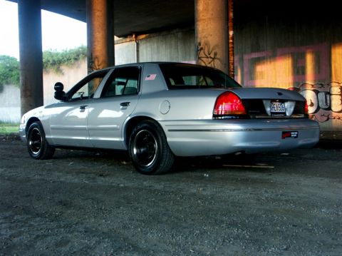 1998 Ford Crown Victoria - This 1998 Ford Crown Victoria is shown from the rear quarter angle, black wheels and an American flag decal on the fender.