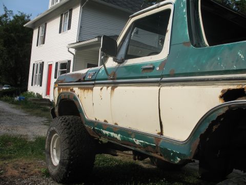 1978 Ford Bronco - This 1978 Ford Bronco shows significant rust and wear, parked outside a residential building.