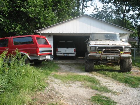 1978 Ford Bronco - A lifted 1978 Ford Bronco is parked in front of a garage, with two other SUVs visible.