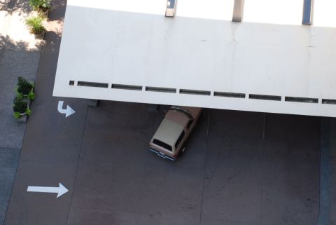 1996 Ford Bronco - A two-tone brown SUV is parked under a modern building's overhang.