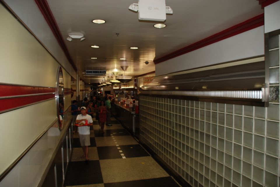 Interior of a diner with checkered floor, glass block wall, and people at a counter