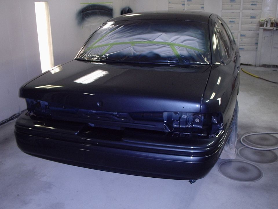 1996 Ford Crown Victoria front end in paint booth, hood and windshield taped off