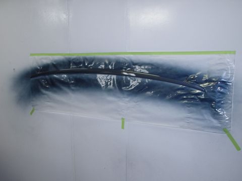 1996 Ford Crown Victoria - A car trim piece is being spray painted in a paint booth, covered in plastic sheeting.