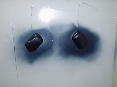 1996 Ford Crown Victoria - Two dark parts are suspended by wires, likely for painting or finishing.