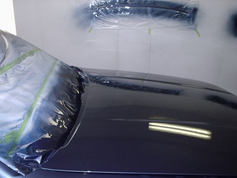 1996 Ford Crown Victoria - A car's hood and windshield area are covered in plastic sheeting and tape, likely during a refinishing process.