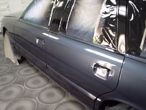 1996 Ford Crown Victoria - A car undergoes a refinishing process, with its windows covered for protection.